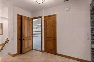 Foyer entrance to garage with baseboards and light tile patterned floors