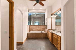 Primary bathroom with a textured wall, ceiling fan, double vanity, a garden tub, and a shower stall