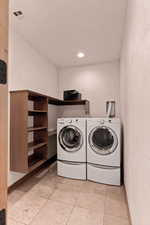 Laundry room (west wing of house) featuring a textured wall, washing machine and dryer, and light tile patterned floors