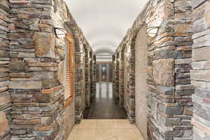 Hallway to right of entry featuring a barrel ceiling and light tile and stained cement flooring