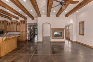 Kitchen featuring recessed lighting, beamed ceiling, glass fronted cabinets, open floor plan, and a ceiling fan