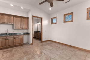 Guest suite with kitchenette, lofted ceiling, ceiling fan, recessed lighting, dark stone countertops, and arched walkways