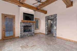 Unfurnished living room featuring ceiling fan, beam ceiling, and a fireplace