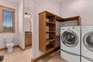 Laundry area featuring a textured wall, washing machine and dryer, and it opens up to a full bathroom