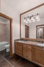 Bathroom featuring double vanity, finished concrete flooring, a textured wall, and shower / bathtub combination