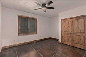 Unfurnished first bedroom with a ceiling fan and a closet