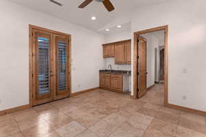 Guest suite with kitchenette, lofted ceiling, ceiling fan, recessed lighting, dark stone countertops, and arched walkways