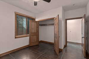 Unfurnished second bedroom featuring ceiling fan, a closet, a textured wall, and a textured ceiling