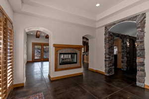 Dining room with hallway to the right that heads to front entry. On the other side of fireplace is a living room and kitchen.