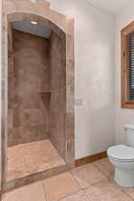 Full bathroom featuring a shower stall, a textured wall, and tile patterned flooring
