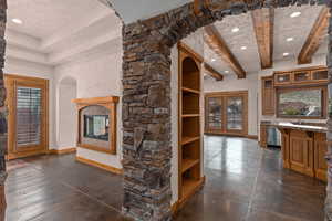 Unfurnished formal dining room, living room, and kitchen with recessed lighting, concrete floors, a fireplace, arched walkways, and french doors
