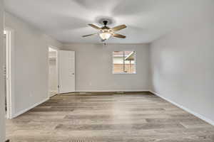 Unfurnished bedroom with a walk in closet, light wood-style flooring, and ceiling fan