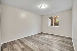 Empty room featuring light wood-style floors and a textured ceiling