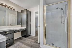 Bathroom featuring light wood finished floors, a shower stall, and vanity