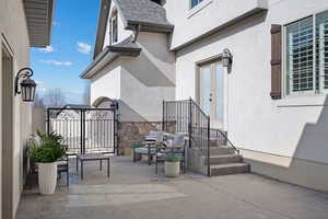 View of exterior entry featuring stucco siding, a gate, and a patio