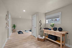 Hallway featuring light wood-type flooring, a textured ceiling, and recessed lighting