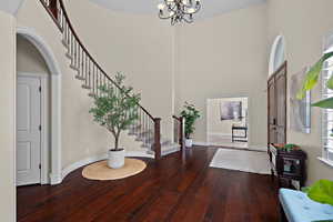 Foyer featuring dark wood-type flooring, a high ceiling, arched walkways, and suspended lighting