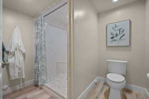 Full bathroom featuring a marble finish shower, light wood finished floors, and recessed lighting
