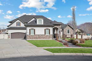 French country home featuring a gate, stone siding, concrete driveway, a shingled roof, and stucco siding
