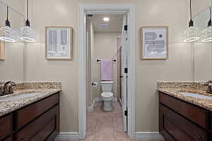 Full bathroom featuring two vanities, a stall shower, and light tile patterned floors