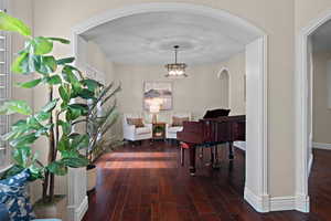 Corridor with dark wood-style floors, arched walkways, and hanging lights