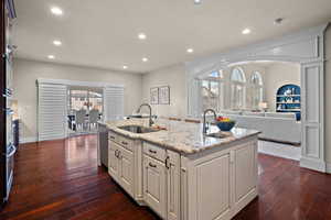 Kitchen with open floor plan, a kitchen island with sink, light stone counters, a textured ceiling, and recessed lighting