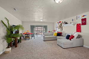 Living area with light colored carpet and a textured ceiling