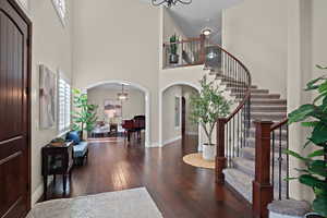 Entryway with arched walkways, suspended lighting, a high ceiling, and dark wood-style floors