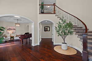 Entrance foyer featuring arched walkways, a high ceiling, and dark wood finished floors