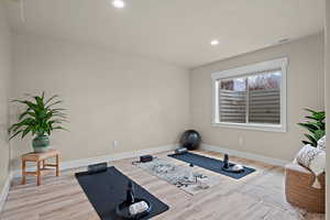Workout area with light wood finished floors and recessed lighting