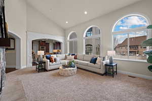 Carpeted living area featuring arched walkways, lofted ceiling, and recessed lighting
