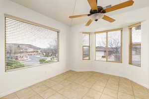 Spare room featuring light tile patterned floors, a ceiling fan, and healthy amount of natural light