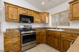 Kitchen featuring gas stove, black microwave, tile countertops, light tile patterned floors, and recessed lighting