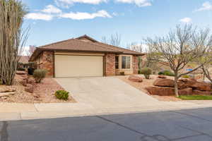 Ranch-style house featuring a garage, concrete driveway, brick siding, and a tiled roof