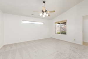 Spare room with light carpet, vaulted ceiling, and a ceiling fan