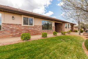 Single story home featuring brick siding, a front lawn, and stucco siding