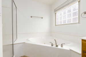 Full bathroom featuring a whirlpool tub, vanity, and a shower stall