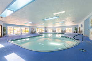 Indoor community pool with a skylight and a community hot tub