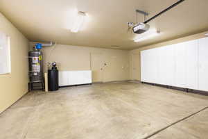 Garage featuring secured water heater and a garage door opener