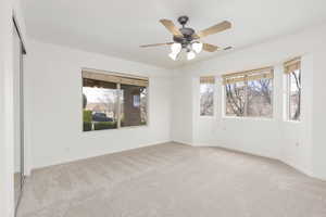 Empty room with light colored carpet and ceiling fan