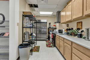 Kitchen with a drop ceiling, light countertops, high end refrigerator, electric range, and light wood finish cabinets