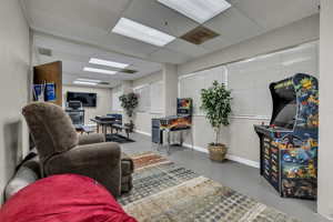 Living room with finished concrete floors and a paneled ceiling
