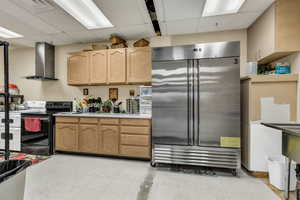 Kitchen with a paneled ceiling, stainless steel refrigerator, electric stove, light countertops, and light wood finish cabinetry