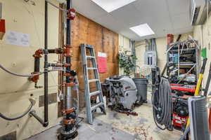 Miscellaneous room with a paneled ceiling, a heating unit, and electric panel