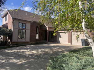 View of front of house featuring brick siding, driveway, a shingled roof, and an attached garage
