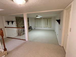 Basement with a stone fireplace, carpet floors, and a textured ceiling