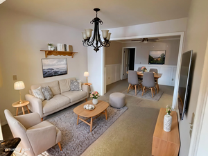 Living area featuring hanging lights, a wainscoted wall, and ceiling fan