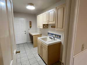 Laundry area featuring light tile patterned floors and a sink