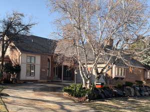 English style home with driveway, a shingled roof, and brick siding