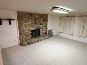 Unfurnished living room featuring carpet flooring and a fireplace